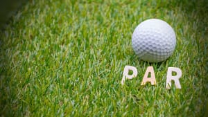 A golf ball rests on the grass with wooden letters spelling "PAR," reflecting the standard score a skilled golfer aims to match. In the world of golf, achieving an under-par score is considered exceptional, leaving players to ponder: what is par in golf truly about?.